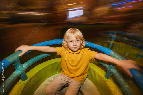 Portrait of little boy looking at camera while riding on a swing in the park