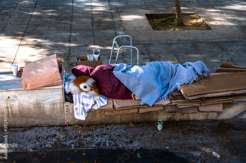 Poor Beggar sleeping on a Street in Athen Greece. Sleeping homeless or beggar old woman over cardboard box.