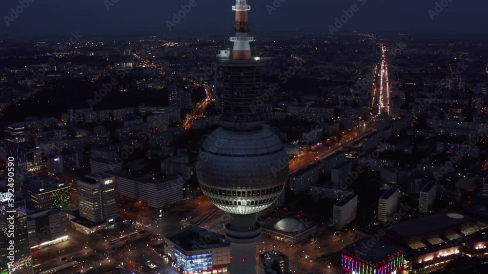 Berlin tall TV Tower at Night blinking red light with Cityscape and road into distance in the background in Germany, Aerial Wide Angle Drone View