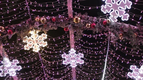 Luminescent bright snowflake coloured light bulbs and flashing garland in light tunnel.Christmas street decorations, new year preparation in city