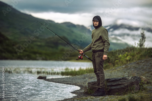 Man fishing with spinning on the bank of scenic mountain lake