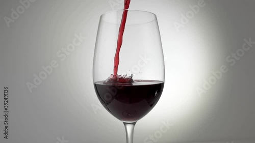Slow motion cinemagraph of red wine being poured into glass