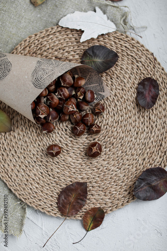 Craft paper bun with baked chestnuts on a jute napkin. Autumn traditional goodies.