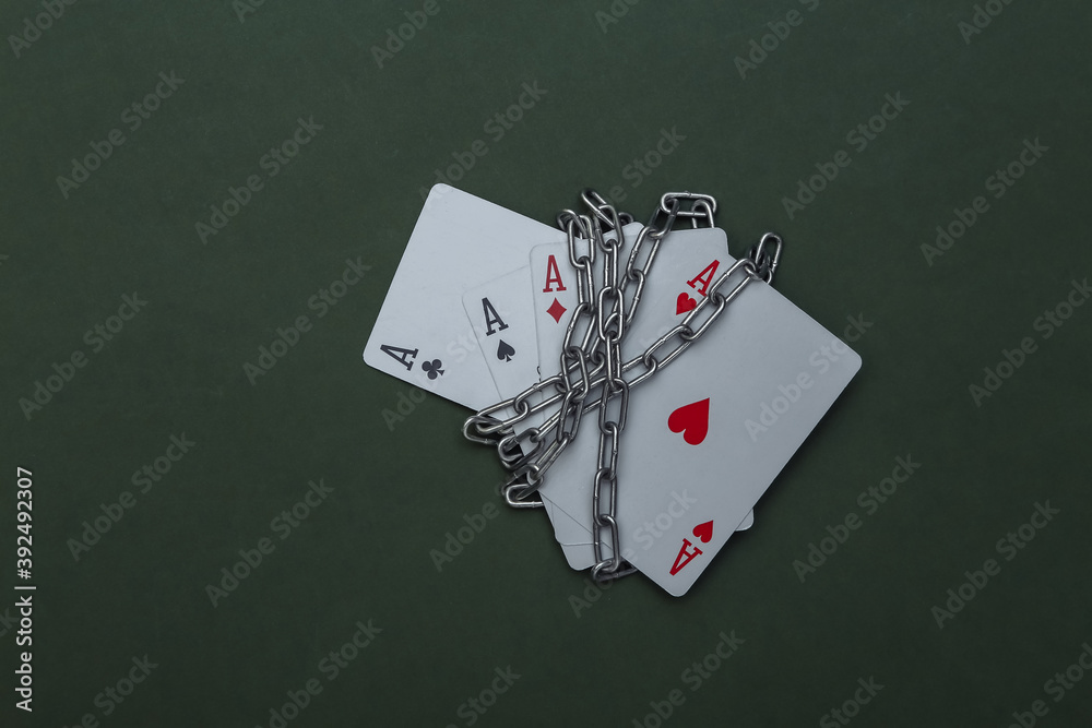 Obraz premium Four aces wrapped in a steel chain on green background. Prohibition of gambling business, casinos