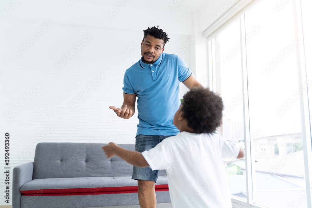 Obraz premium African American father dancing and playing with cute curly little son in room at home. Happy African family spending time together on holiday at home. family, kid and holiday concept