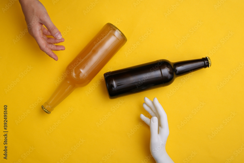 Naklejka premium Human and mannequin hand touching beer bottle on yellow background