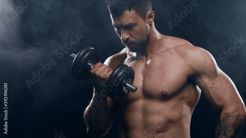 Fit and sporty bodybuilder over black background. Sportsman in studio. Sport and fitness concepts. © Acronym