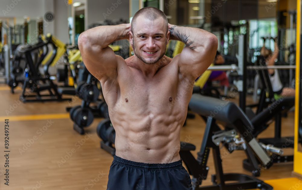Naklejka premium Muscular male bodybuilder with naked torso posing in the gym