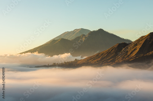 Sunrise view of mount Batur, Abang and Agung volcano in Bali from Pinggan village. Beautiful sunrise and low clouds. Layered minimalist landscape. photo