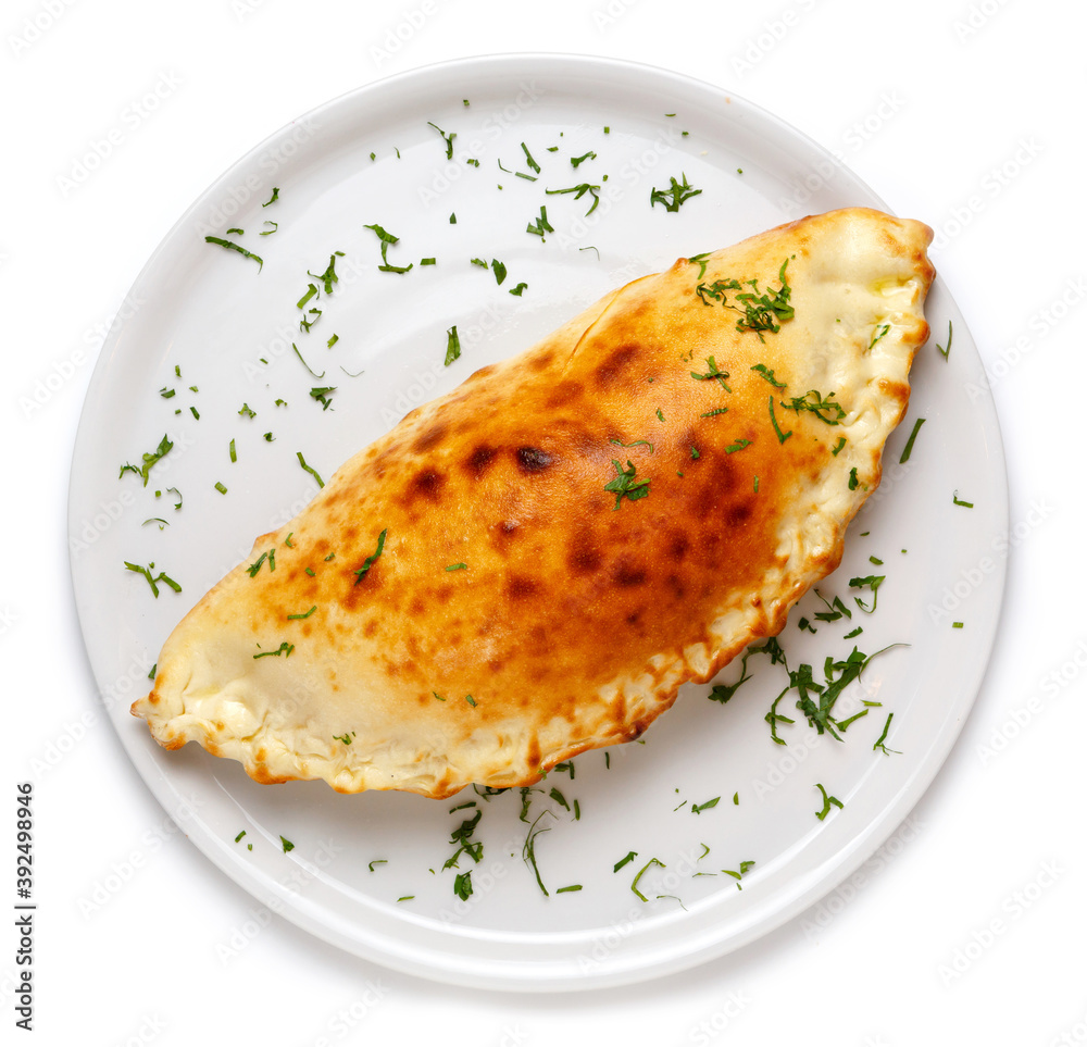 Italian closed pizza Calzone on a large white plate, isolated on white background Italian closed pizza Calzone on a large white plate, isolated on white background