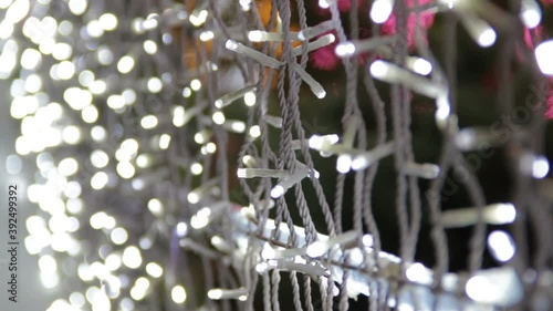 Decor of a street with LED bulb close up hand-held video.Happy New Year and Xmas theme. Alley with blurred shimmering garland lights, abstract blurry background.Shallow depth of field