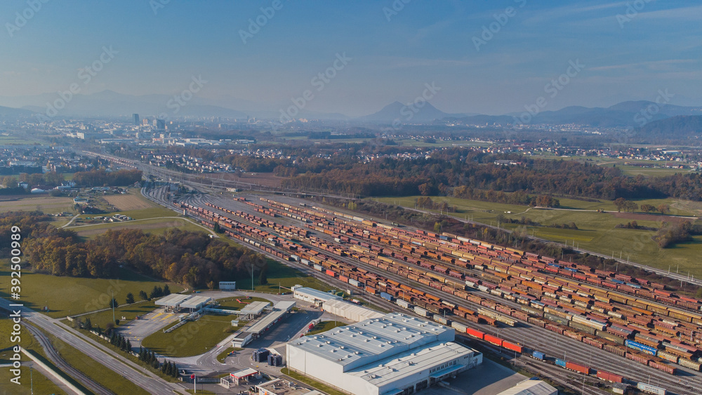 Aerial photo of a train marshalling yard on a warm day in autumn. Visible a large amount of train tracks and freight cars.