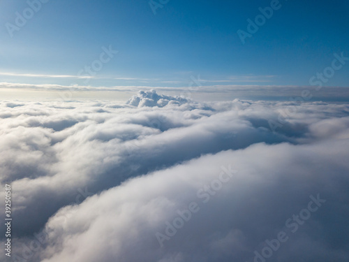 Aerial view. Flying over white clouds during the day in sunny weather. © Sergey