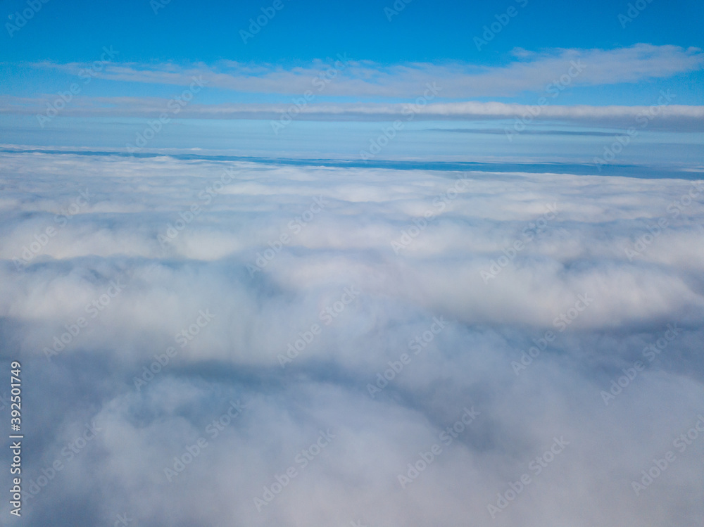 Obraz premium Aerial view. Flying over white clouds during the day in sunny weather.