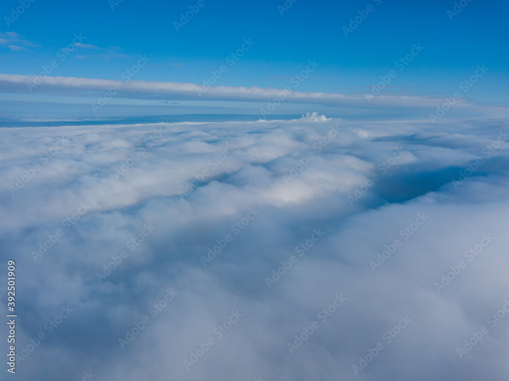 Fototapeta premium Aerial view. Flying over white clouds during the day in sunny weather.