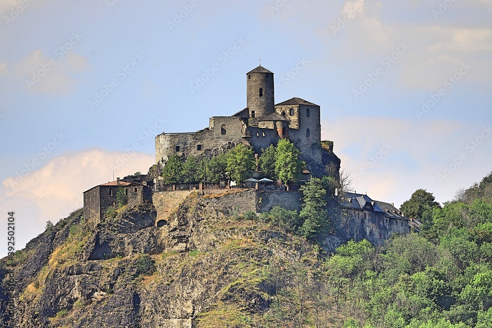 a dilapidated castle on top of a high cliff above the river