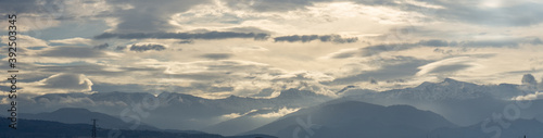 Panoramic view of Sierra Nevada between clouds (some of them lenticular) and sunbeams at sunrise © Miguel Ángel RM
