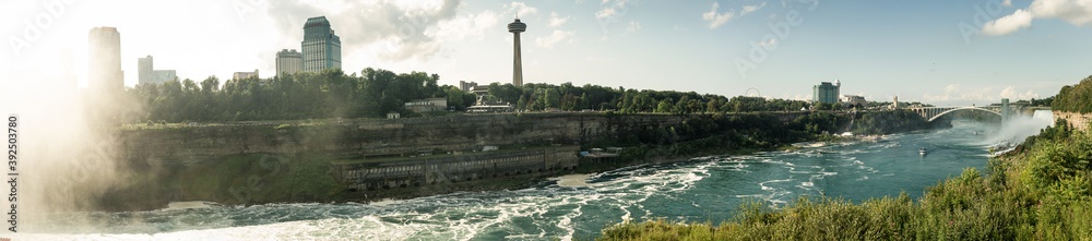 Panorama view of Rainbow Bridge over Niagara river and sightseeing boat below together with American falls