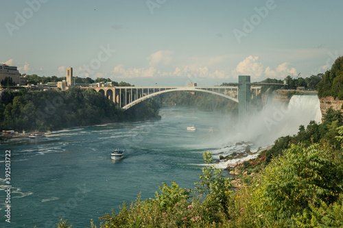 Panorama view of Rainbow Bridge over Niagara river and sightseeing boat below together with American falls
