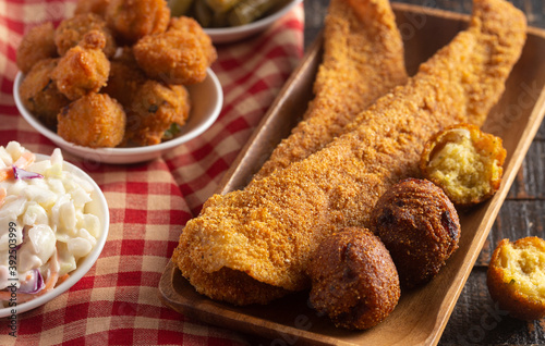 Obraz na plátne Breaded and Fried Fillets of Fish with Hushpuppies on a Wooden Table