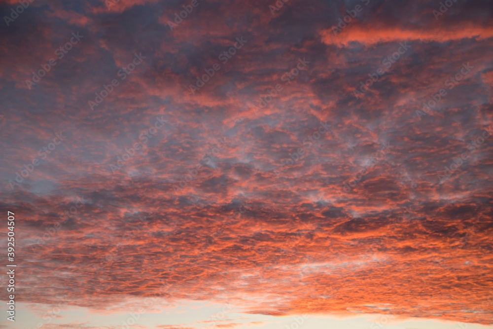 Beautiful red-orange sky with small clouds torn to shreds at sunset. Horizontal orientation.