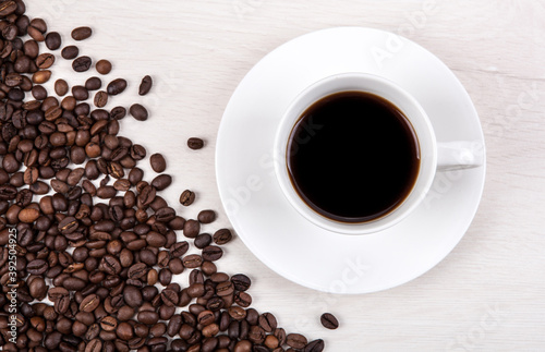 cup of coffee on a grey wooden background and roasted coffee bea