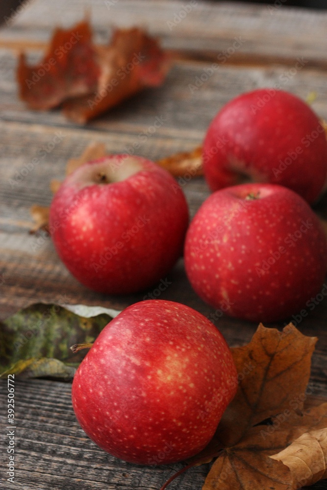 Juicy red apples and autumn leaves on the table Juicy red apples and autumn leaves on the table