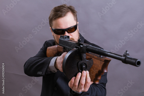 Mature man in sunglasses dressed in suit with tommy gun © idea_studio