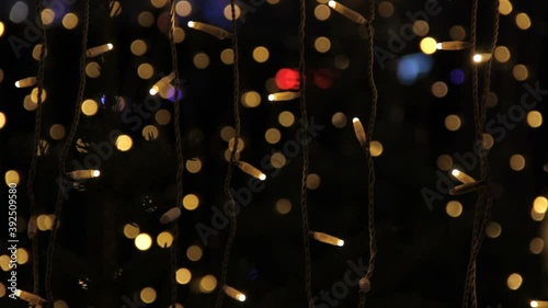 Close up of coloured light bulbs in light tunnel. Christmas street decorations, new year preparation in city. Abstract blurry background.