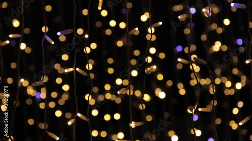 Close up of coloured light bulbs in light tunnel. Christmas street decorations, new year preparation in city. Abstract blurry background.