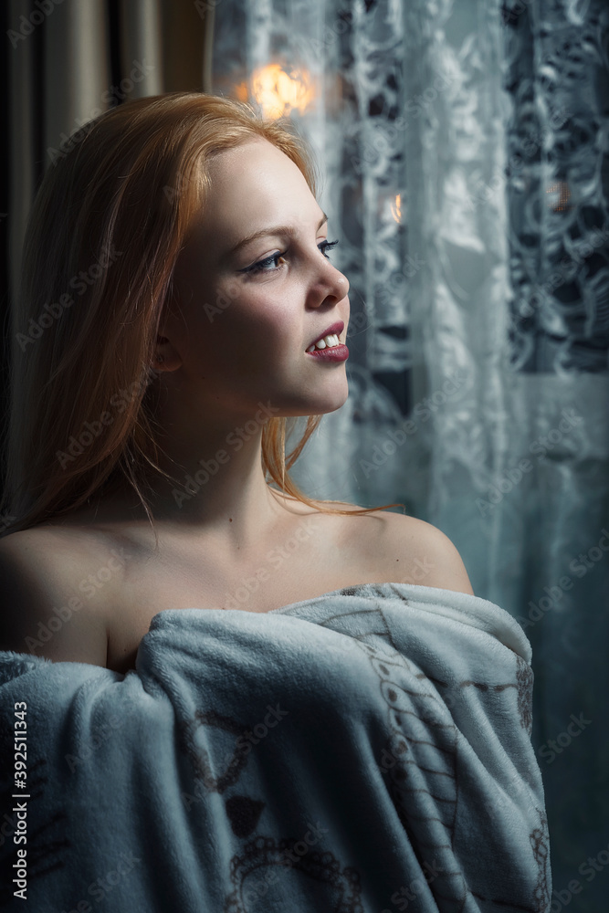 beautiful girl stands at the window at night wrapped in a plaid beautiful girl stands at the window at night wrapped in a plaid