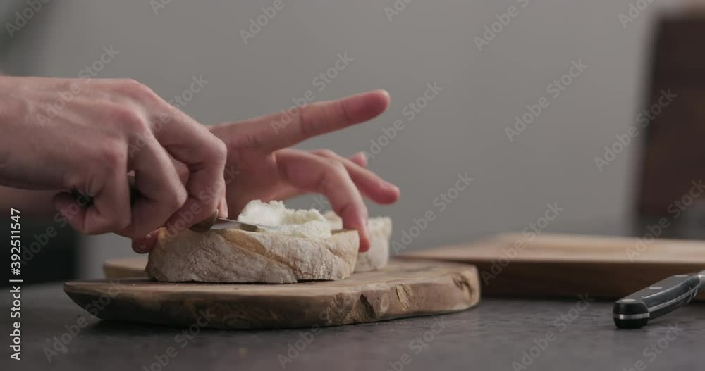 Slow motion man makes sandwich with cream cheese on olive board
