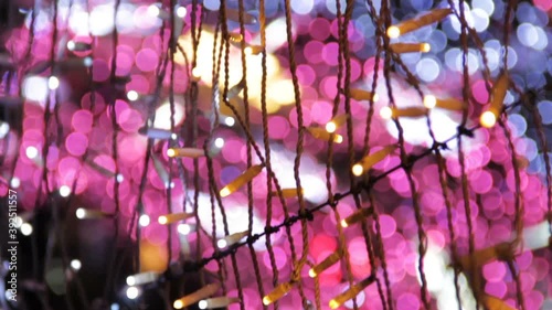 Close up of coloured light bulbs in light tunnel. Christmas street decorations, new year preparation in city. Abstract blurry background.
