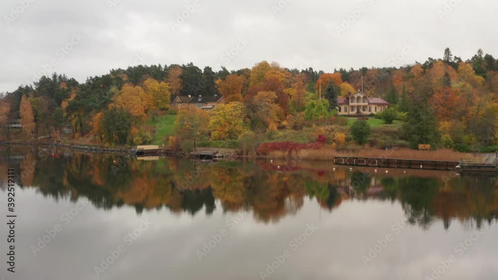 Lake and house in autumn. Wooden luxurious old home between trees and mirror on water surface Lake and house in autumn. Wooden luxurious old home between trees and mirror on water surface