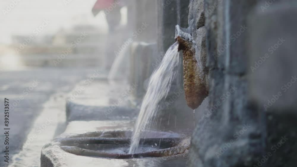stone hot springs pouring boiling water. burgas of orense. blur stone background. water jet with silk effect and steam