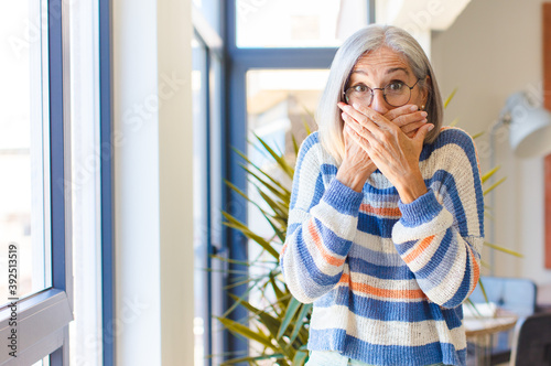 Cuadro en lienzo middle age woman covering mouth with hands with a shocked, surprised expression,