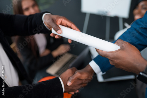 Close-up of a handshake of two African American men. The investor signed the contract and hands it over to the business partner © DmitryStock