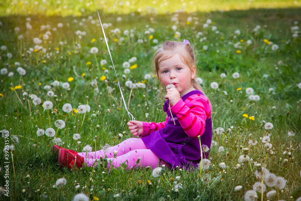 Little girl in a clearing with dandelions in spring on a Sunny day. Happy childhood. Little girl in a clearing with dandelions in spring on a Sunny day. Happy childhood.