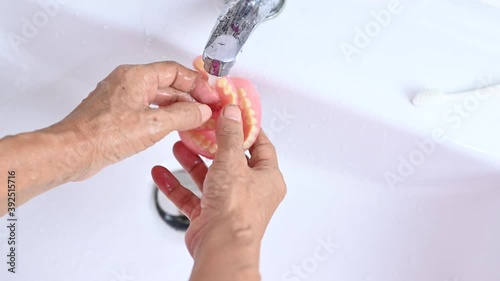 The old woman's hands clean the dentures
