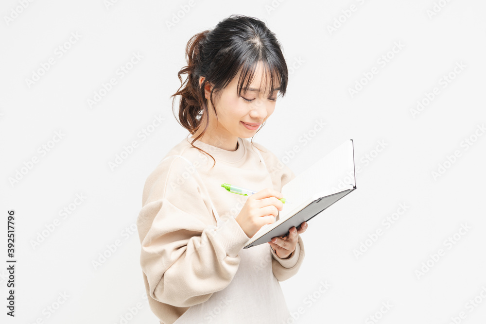 ノートにメモを書く若い女性