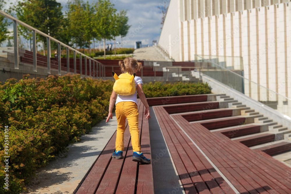 Little Girl in Yellow Jeans Runs Through the Park Little Girl in Yellow Jeans Runs Through the Park