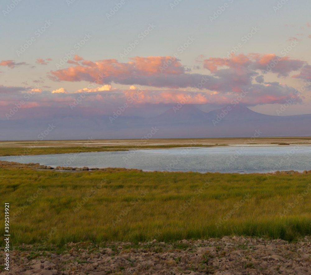 Sunset over salt lake in Atacama desert with orange mountains, Chile