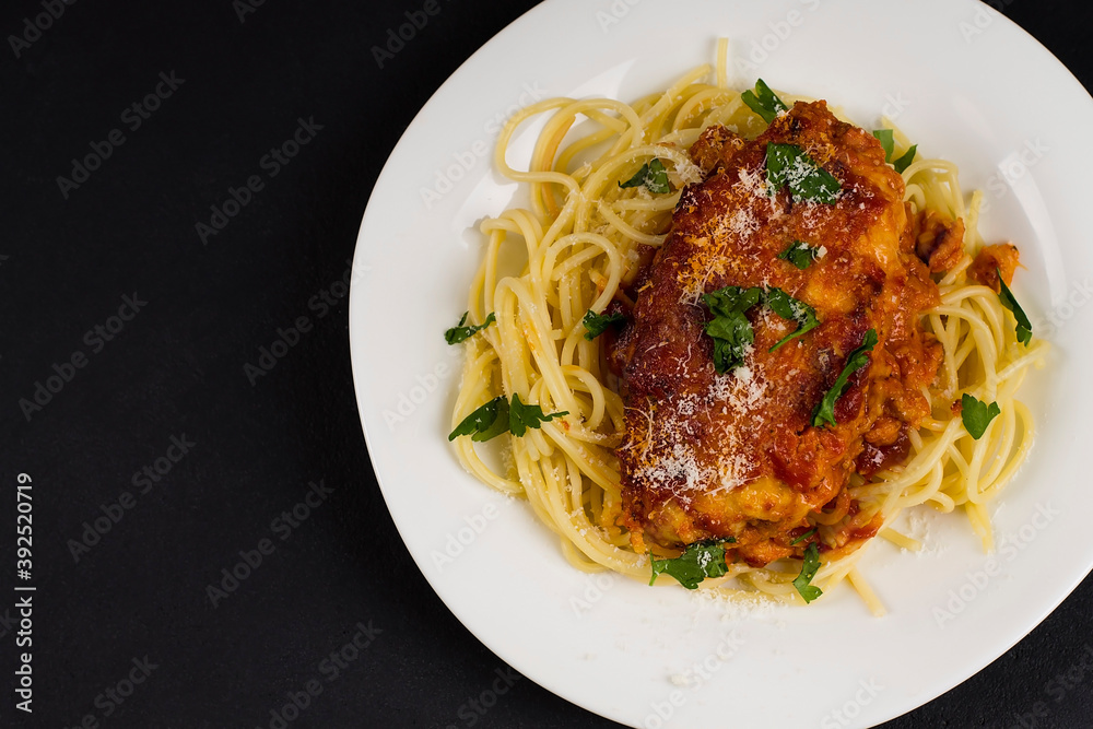 Chicken parmigiana on a white plate with spaghetti. View from above