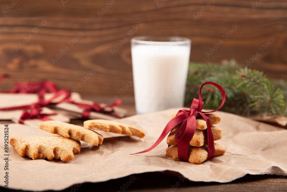 Christmas gingerbread cookies and a cup of milk on dark wooden background.