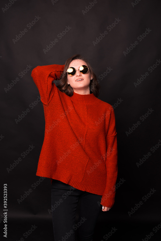 A portrait of a young woman in sweater with sun glasses posing in front of camera . A portrait of a young woman in sweater with sun glasses posing in front of camera .