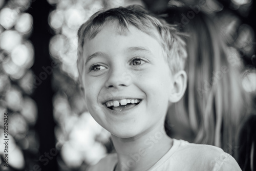 Black and white outdoor portrait of a cute seven years old boy.