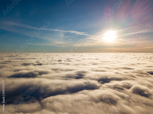 Aerial high flight over curly clouds. The sun s rays shine on the clouds.