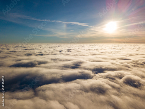 Aerial high flight over curly clouds. The sun s rays shine on the clouds.