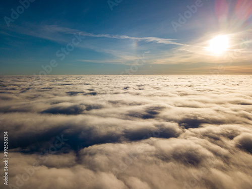 Aerial high flight over curly clouds. The sun s rays shine on the clouds.