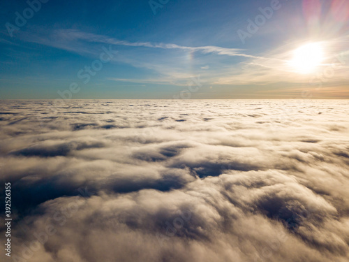 Aerial high flight over curly clouds. The sun s rays shine on the clouds.